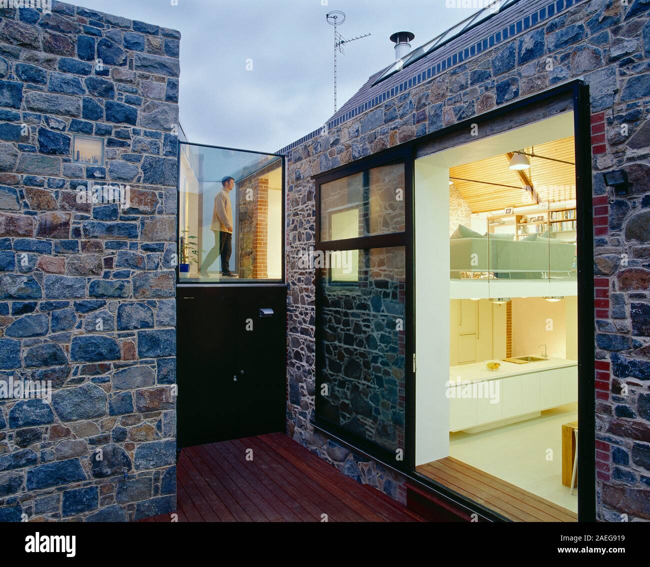 Architettura. Moderno design esterno della casa con pareti di granito e vista attraverso le finestre dell'interno. Foto Stock