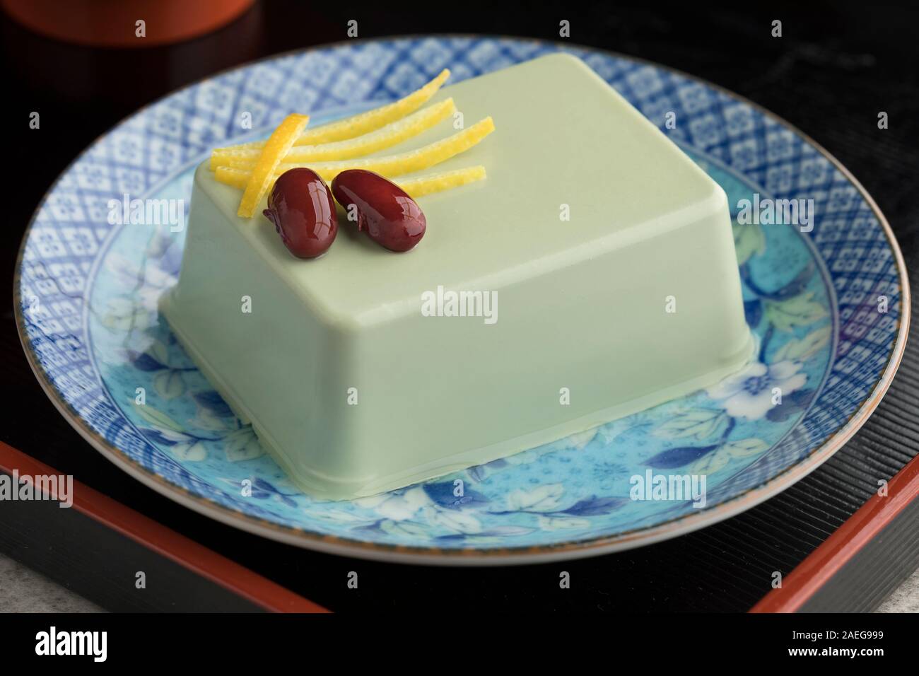 Pezzo di giapponese matcha il tofu su un piatto decorato con limone e fagioli dolci Foto Stock