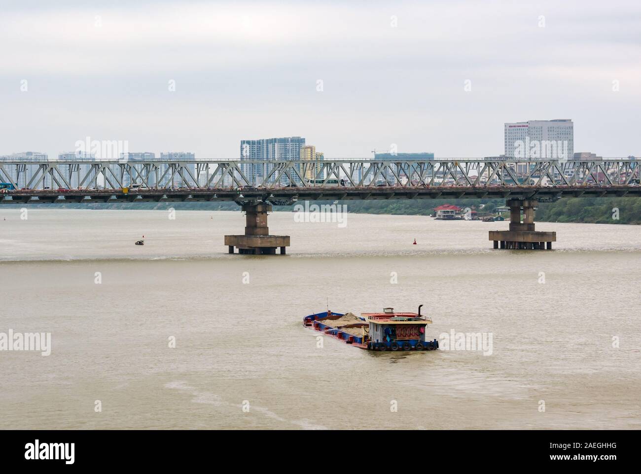 Bassa giacente chiatte che trasportano sabbia, Red River con Chuong Duong Bridge, Hanoi, Vietnam Foto Stock