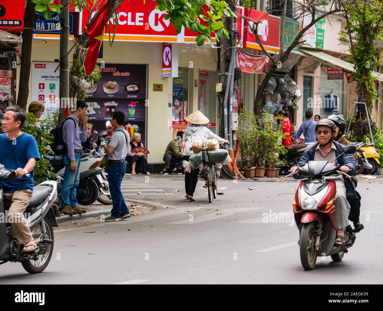 Il vietnamita donna che indossa cappello conico spingendo bicycle & moto, Hanoi, Vietnam Asia Foto Stock