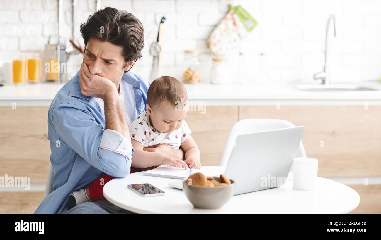 Sottolineato uomo seduto con suo Figlio bambino in cucina, non riesco a lavorare Foto Stock