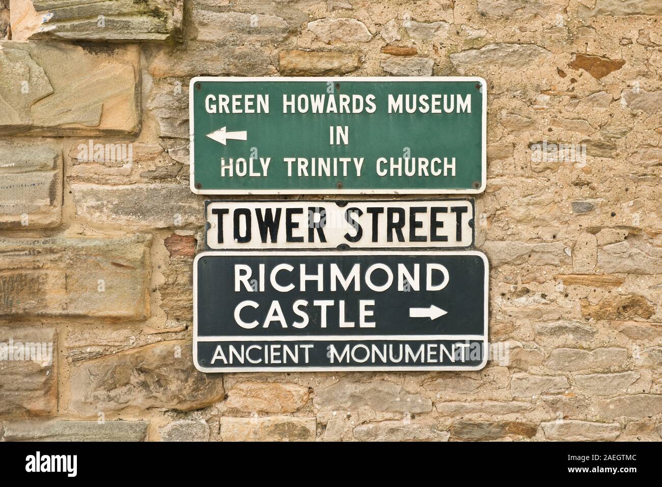 Via segni sulla parete della torre Street di Richmond per il Green Howards Museum, Chiesa della Santa Trinità e Richmond Castle. North Yorkshire, Inghilterra Foto Stock