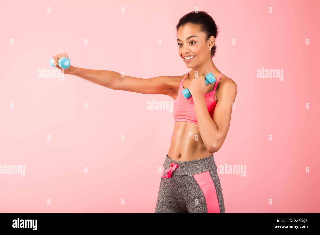 African American Girl Holding manubri e boxe su sfondo rosa Foto Stock