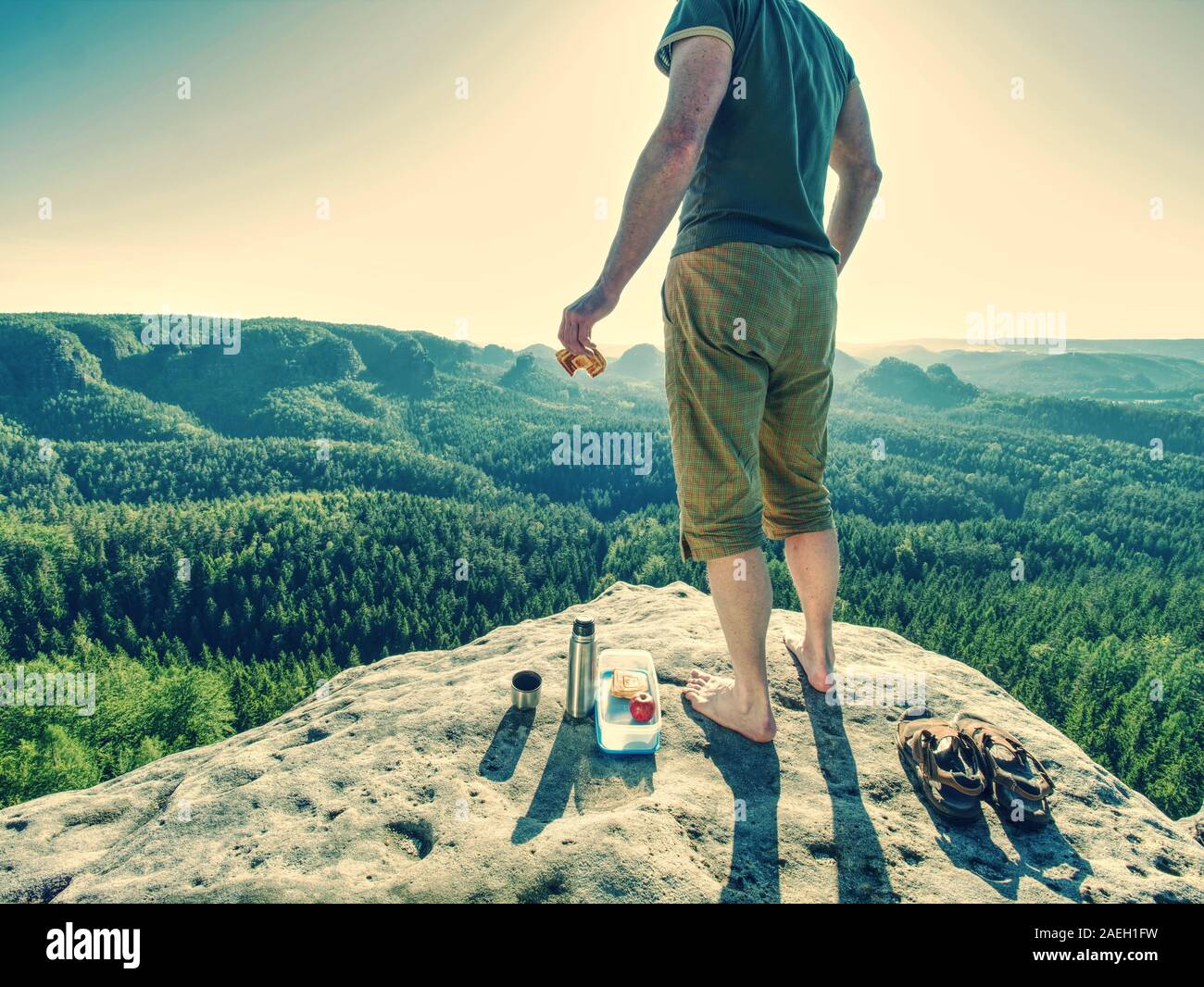 La mezza età guy hanno la colazione sulla vetta rocciosa. Lo sport e la motivazione del tema. Mattina di sole meteo. Foto Stock