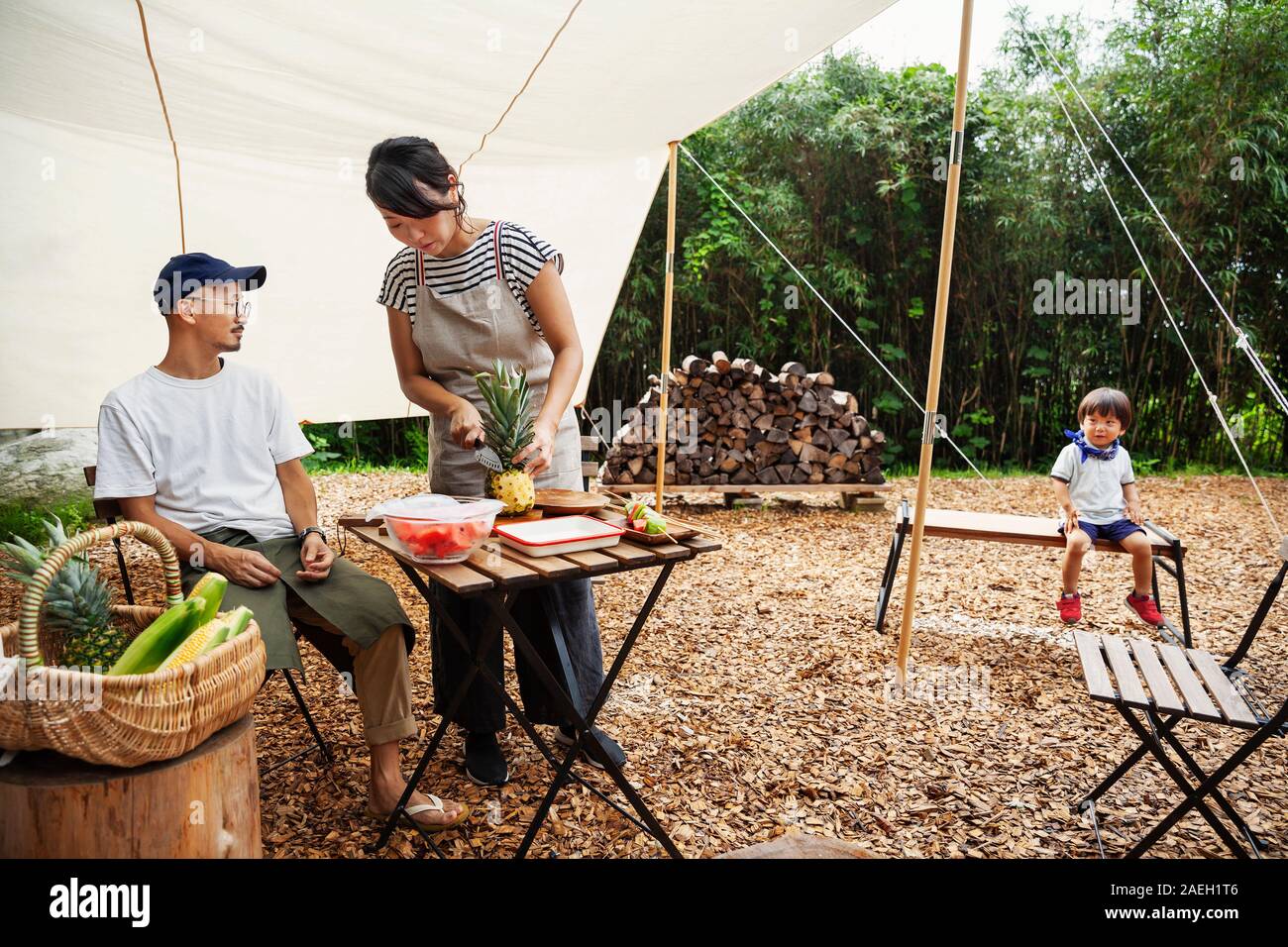 Giapponese, uomo donna e bambino si sono riuniti intorno ad un tavolo sotto una tettoia, preparare verdura. Foto Stock