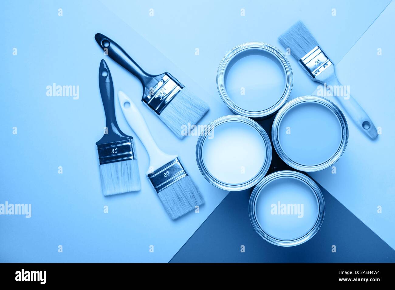 Quattro apri barattoli di vernice con spazzole su sfondo blu. Colore principale dell'anno 2020 in interni Foto Stock