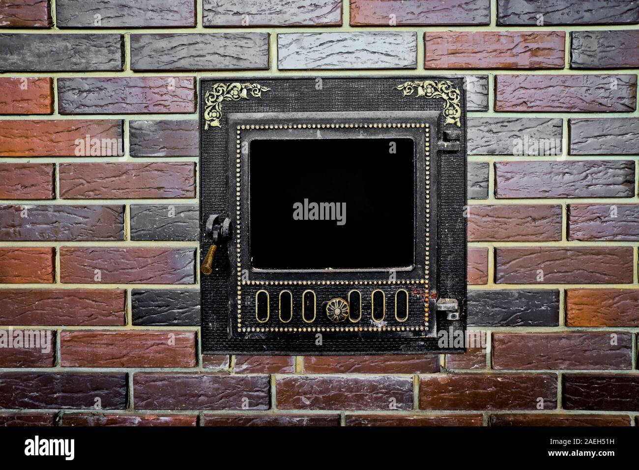 Forno ghisa porta con un modello in rilievo nel muro di fuoco mattone nella sauna. Texture di un muro di mattoni. Foto Stock