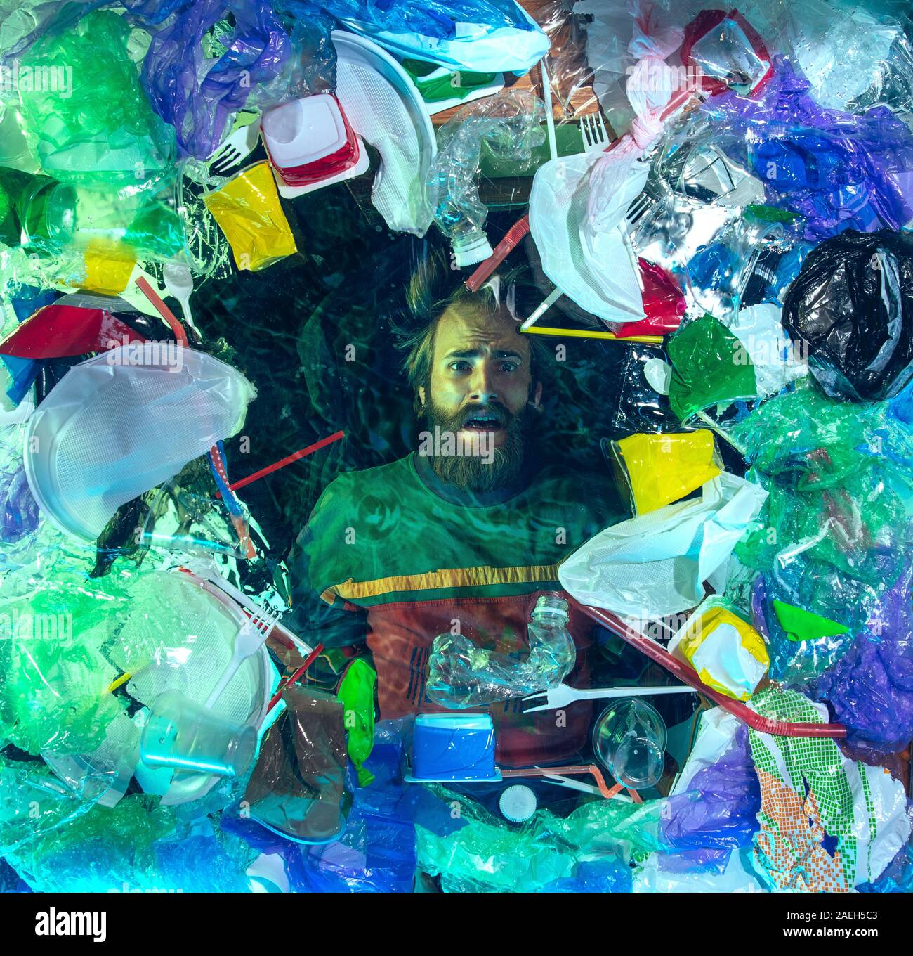 L'uomo annegamento in acqua sotto plastica destinatari pila, garbage. Utilizzate bottiglie e pacchi di riempimento oceano mondiale uccisione di persone. Ecologia, Ambiente concetto, plastica e vetro inquinamento, natura disastro. Foto Stock