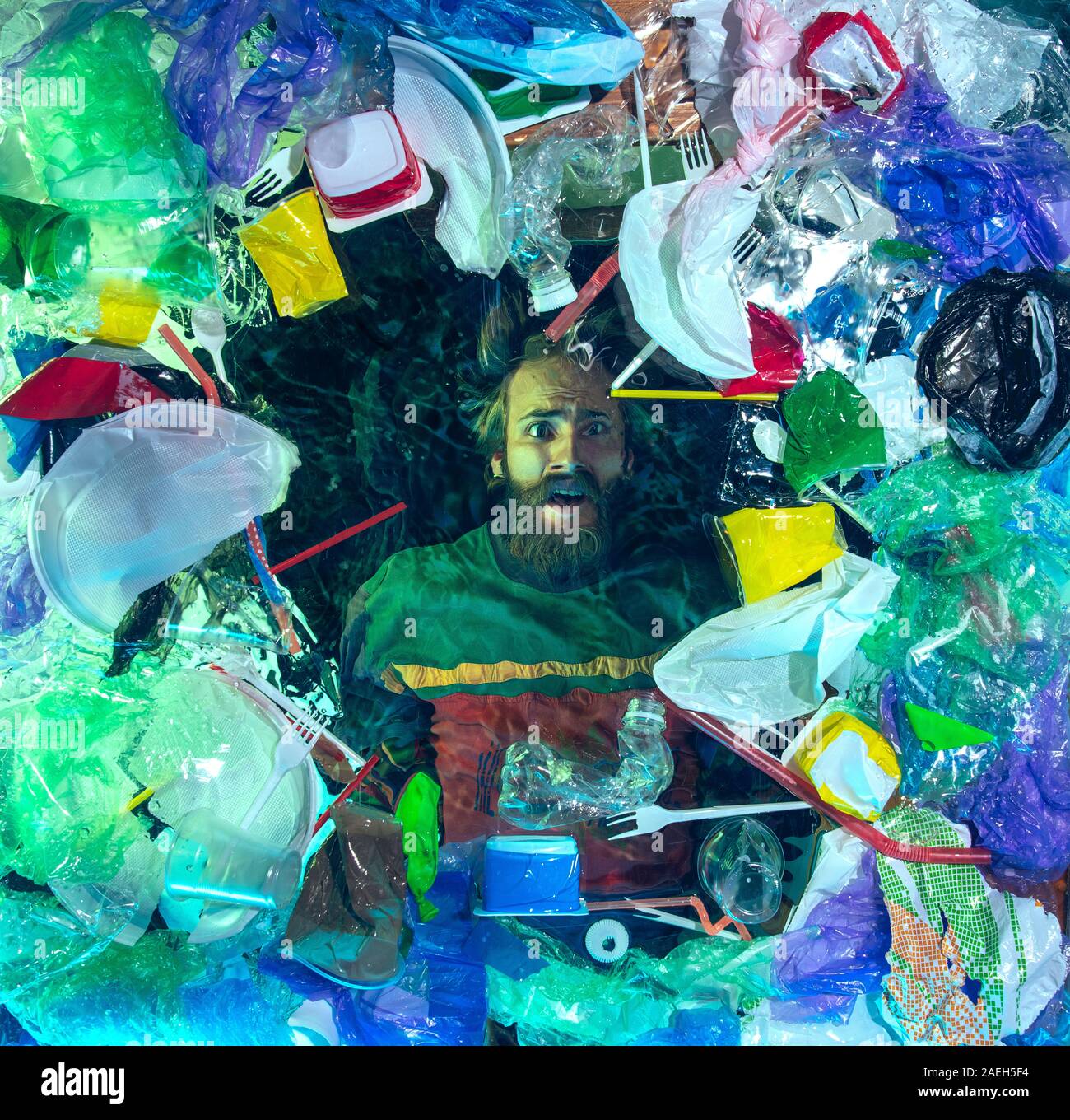 L'uomo annegamento in acqua sotto plastica destinatari pila, garbage. Utilizzate bottiglie e pacchi di riempimento oceano mondiale uccisione di persone. Ecologia, Ambiente concetto, plastica e vetro inquinamento, natura disastro. Foto Stock