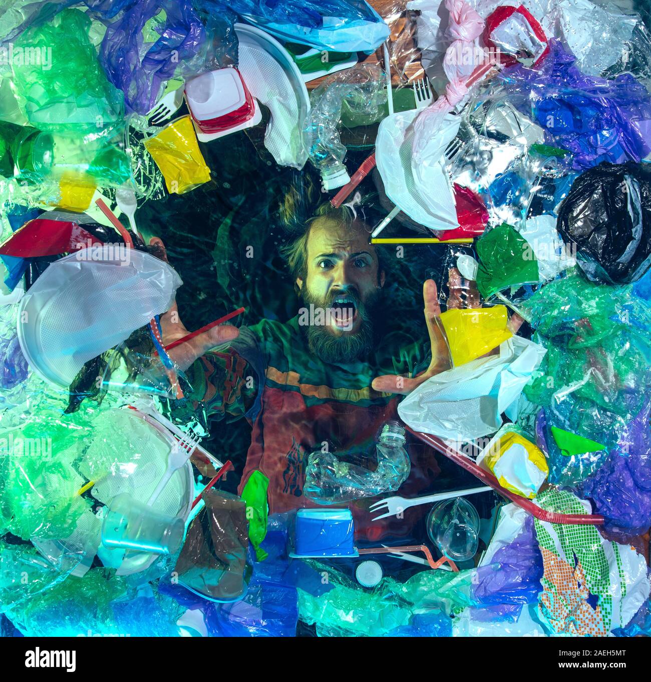 L'uomo annegamento in acqua sotto plastica destinatari pila, garbage. Utilizzate bottiglie e pacchi di riempimento oceano mondiale uccisione di persone. Ecologia, Ambiente concetto, plastica e vetro inquinamento, natura disastro. Foto Stock