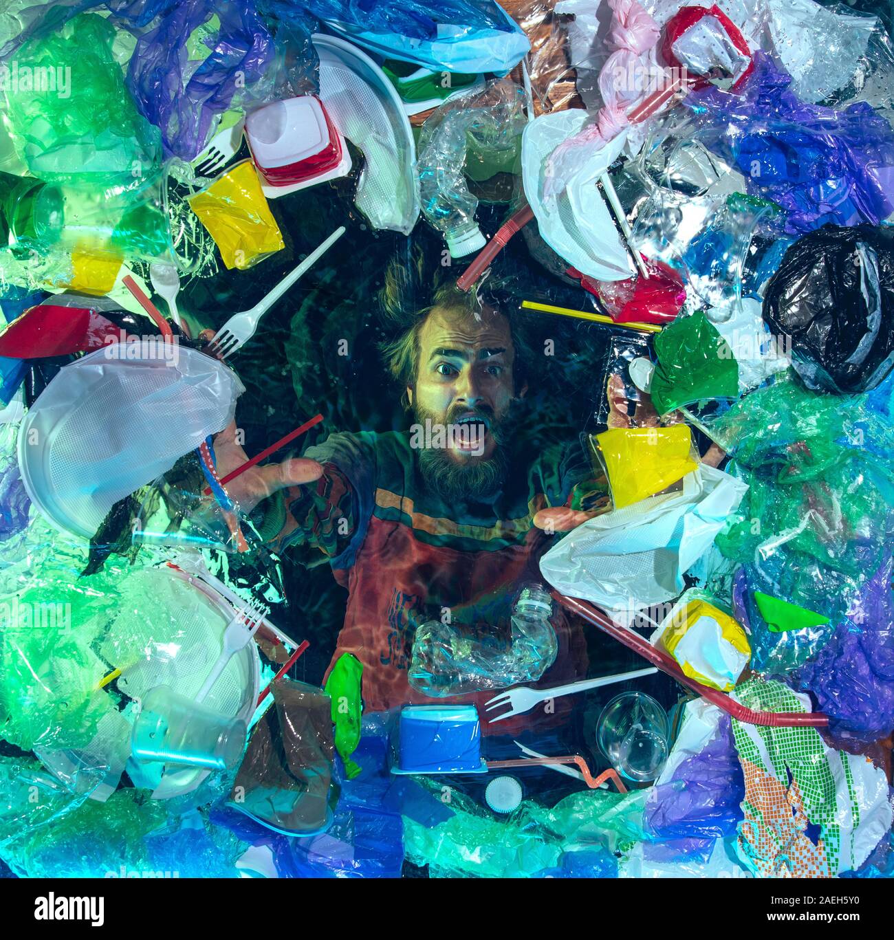 L'uomo annegamento in acqua sotto plastica destinatari pila, garbage. Utilizzate bottiglie e pacchi di riempimento oceano mondiale uccisione di persone. Ecologia, Ambiente concetto, plastica e vetro inquinamento, natura disastro. Foto Stock