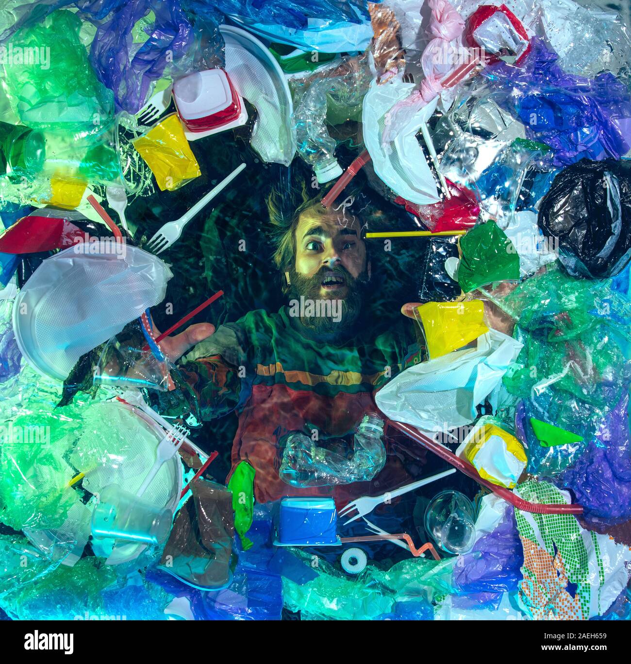 L'uomo annegamento in acqua sotto plastica destinatari pila, garbage. Utilizzate bottiglie e pacchi di riempimento oceano mondiale uccisione di persone. Ecologia, Ambiente concetto, plastica e vetro inquinamento, natura disastro. Foto Stock