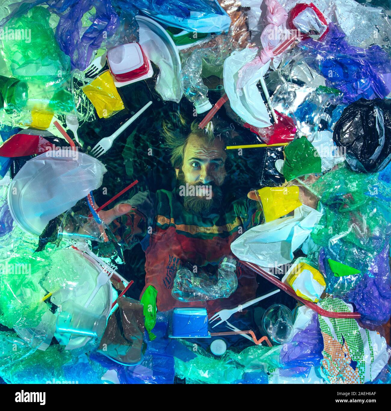 L'uomo annegamento in acqua sotto plastica destinatari pila, garbage. Utilizzate bottiglie e pacchi di riempimento oceano mondiale uccisione di persone. Ecologia, Ambiente concetto, plastica e vetro inquinamento, natura disastro. Foto Stock