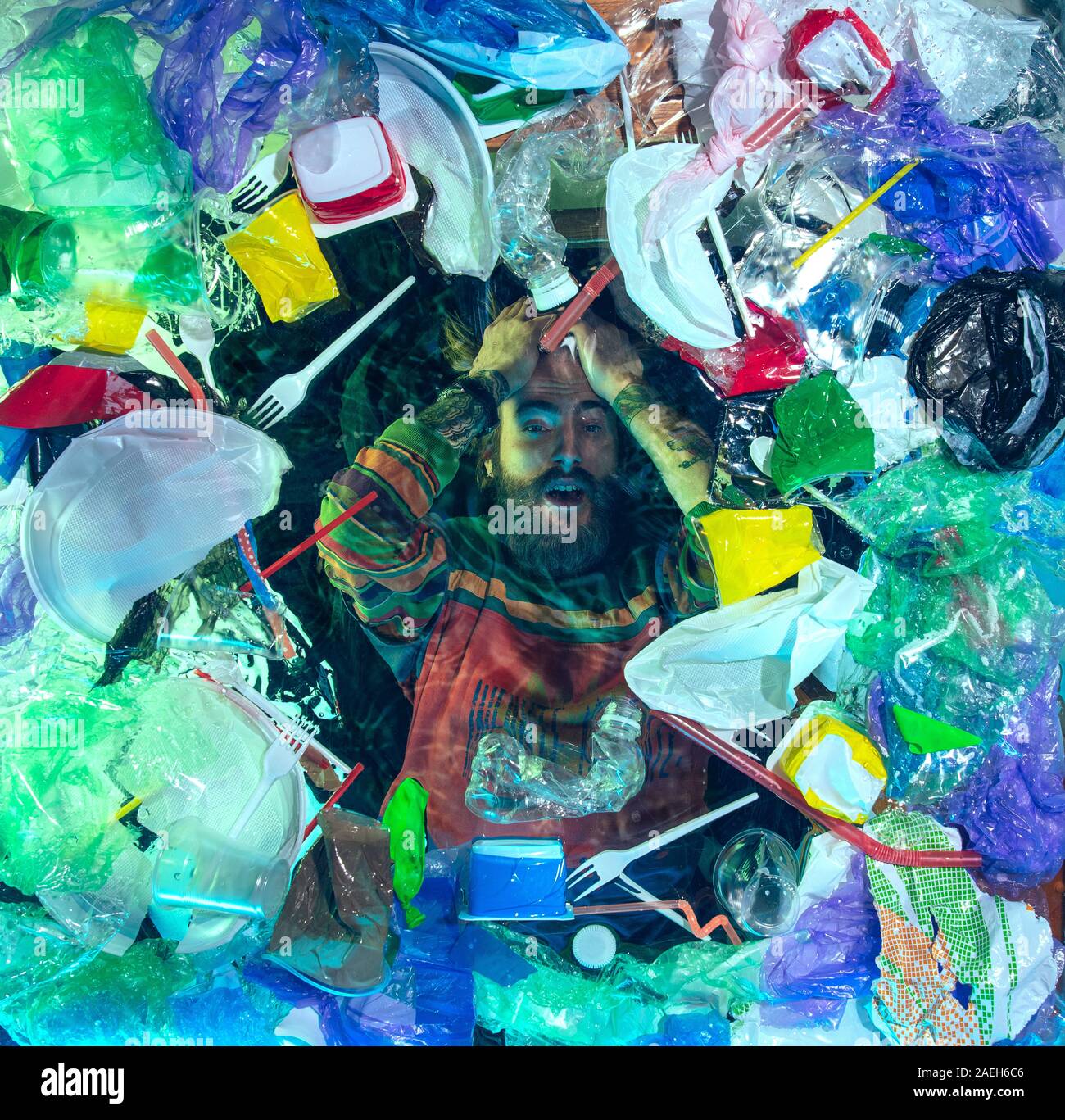 L'uomo annegamento in acqua sotto plastica destinatari pila, garbage. Utilizzate bottiglie e pacchi di riempimento oceano mondiale uccisione di persone. Ecologia, Ambiente concetto, plastica e vetro inquinamento, natura disastro. Foto Stock