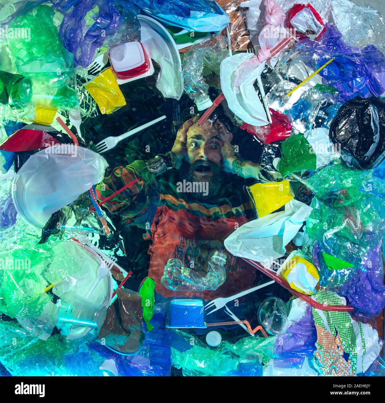 L'uomo annegamento in acqua sotto plastica destinatari pila, garbage. Utilizzate bottiglie e pacchi di riempimento oceano mondiale uccisione di persone. Ecologia, Ambiente concetto, plastica e vetro inquinamento, natura disastro. Foto Stock