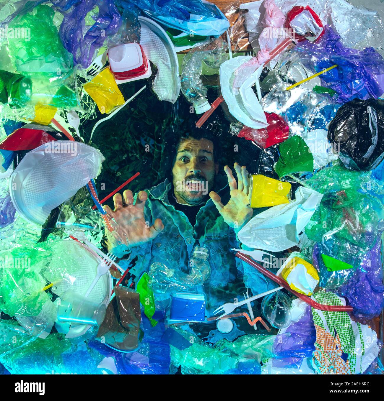 L'uomo annegamento in acqua sotto plastica destinatari pila, garbage. Utilizzate bottiglie e pacchi di riempimento oceano mondiale uccisione di persone. Ecologia, Ambiente concetto, plastica e vetro inquinamento, natura disastro. Foto Stock