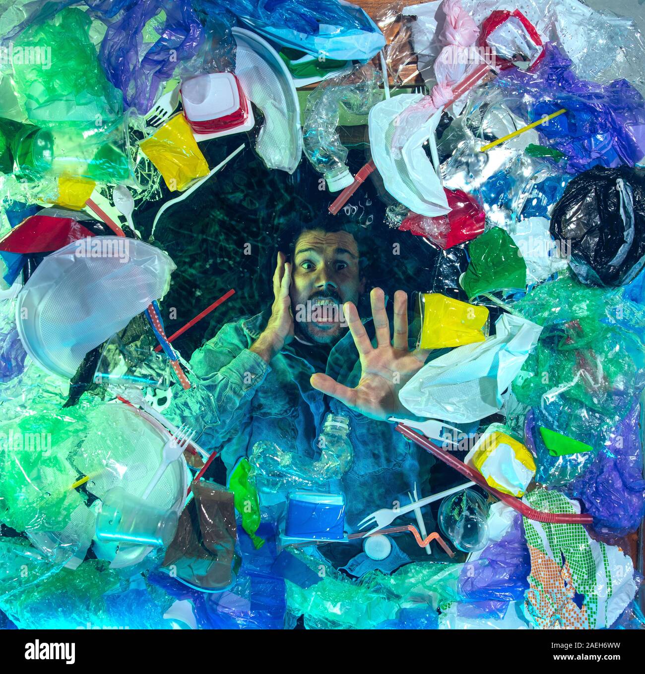 L'uomo annegamento in acqua sotto plastica destinatari pila, garbage. Utilizzate bottiglie e pacchi di riempimento oceano mondiale uccisione di persone. Ecologia, Ambiente concetto, plastica e vetro inquinamento, natura disastro. Foto Stock