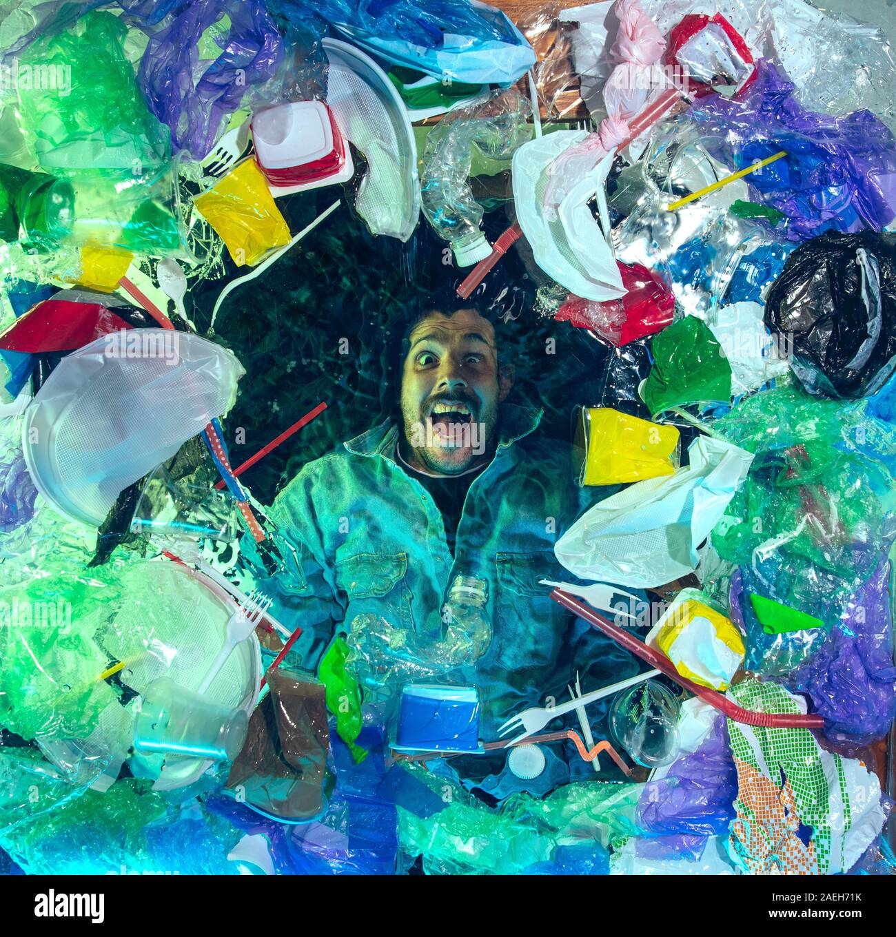 L'uomo annegamento in acqua sotto plastica destinatari pila, garbage. Utilizzate bottiglie e pacchi di riempimento oceano mondiale uccisione di persone. Ecologia, Ambiente concetto, plastica e vetro inquinamento, natura disastro. Foto Stock