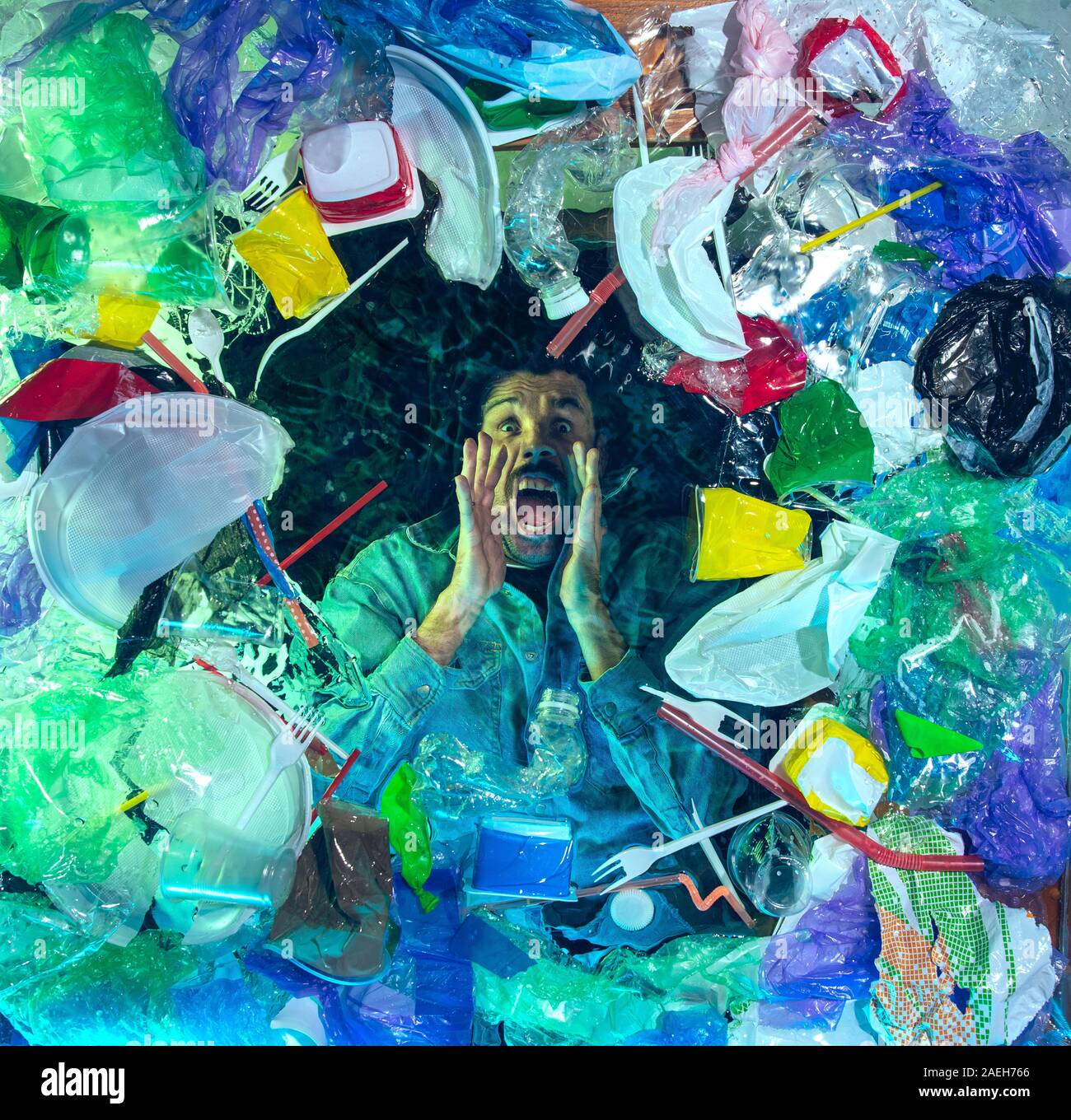 L'uomo annegamento in acqua sotto plastica destinatari pila, garbage. Utilizzate bottiglie e pacchi di riempimento oceano mondiale uccisione di persone. Ecologia, Ambiente concetto, plastica e vetro inquinamento, natura disastro. Foto Stock