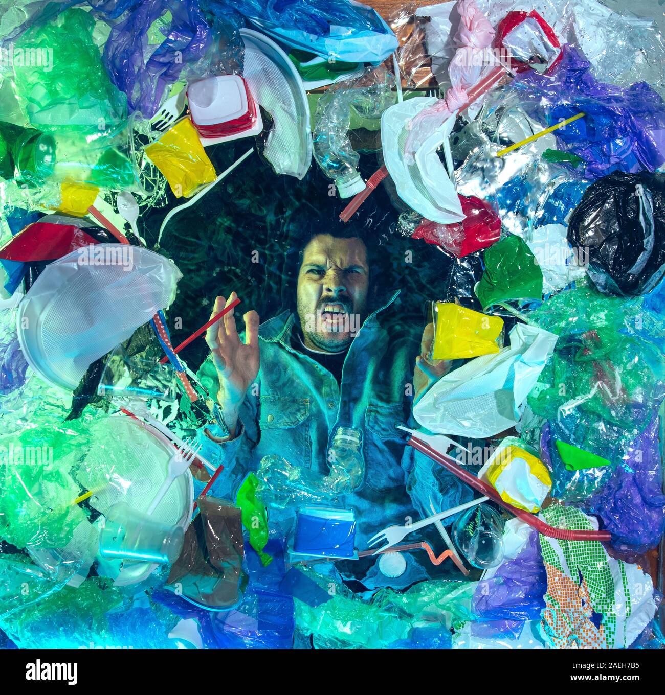 L'uomo annegamento in acqua sotto plastica destinatari pila, garbage. Utilizzate bottiglie e pacchi di riempimento oceano mondiale uccisione di persone. Ecologia, Ambiente concetto, plastica e vetro inquinamento, natura disastro. Foto Stock