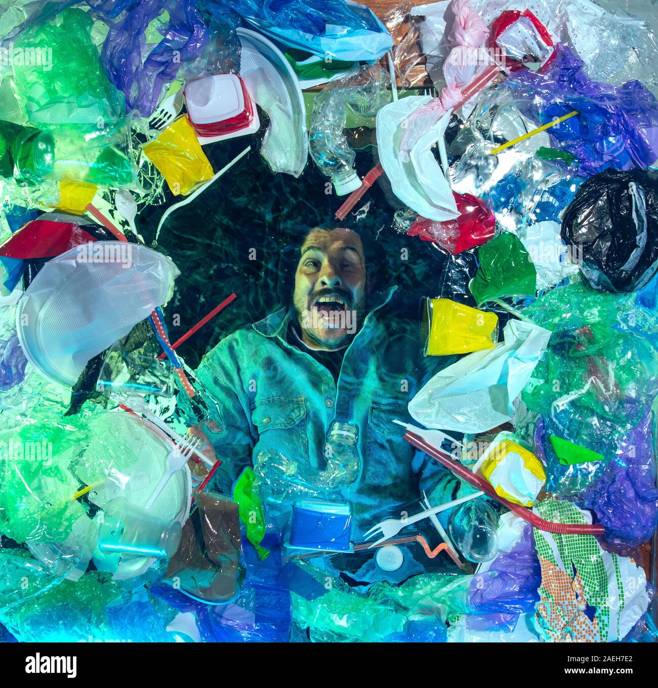 L'uomo annegamento in acqua sotto plastica destinatari pila, garbage. Utilizzate bottiglie e pacchi di riempimento oceano mondiale uccisione di persone. Ecologia, Ambiente concetto, plastica e vetro inquinamento, natura disastro. Foto Stock