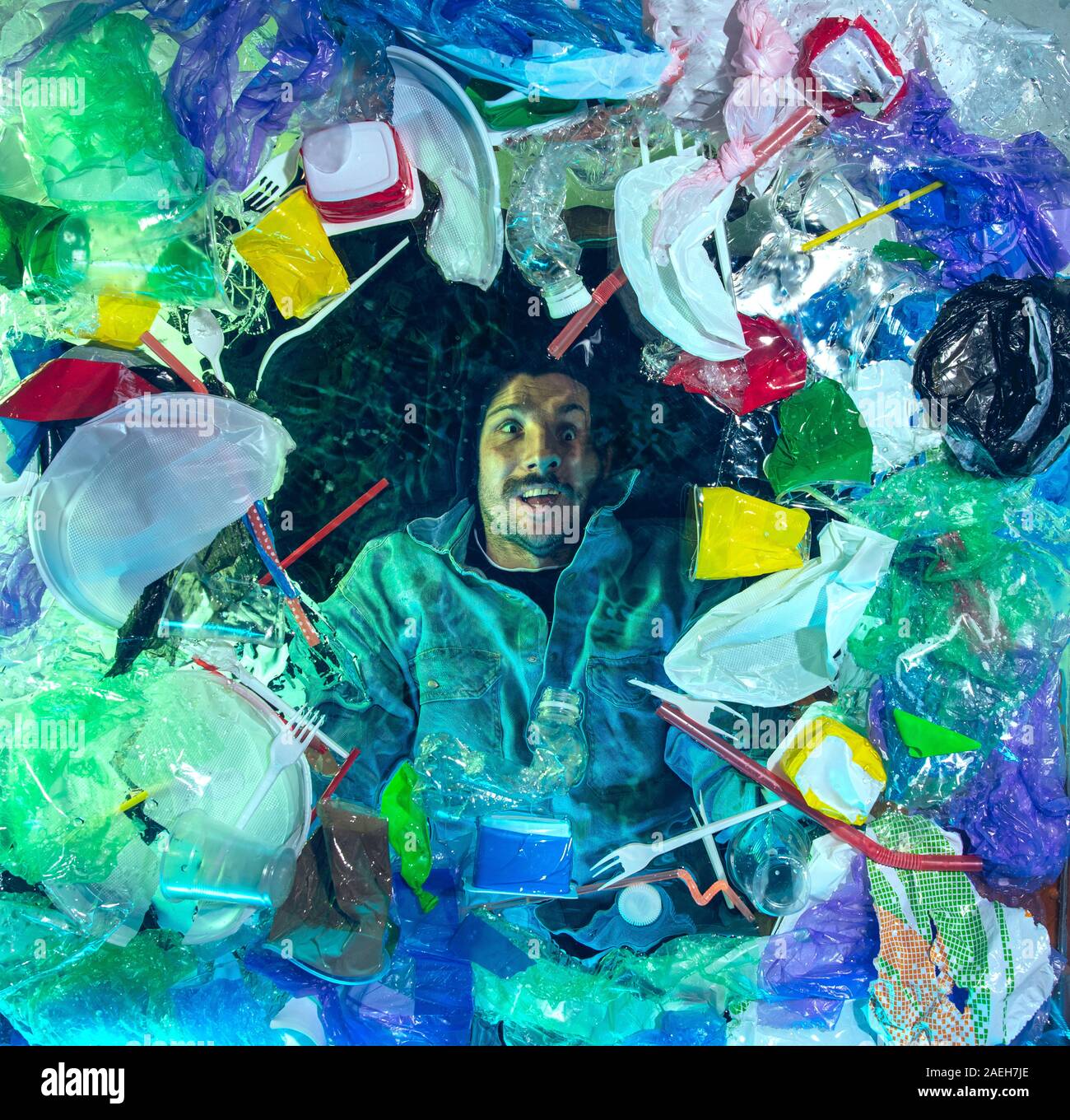 L'uomo annegamento in acqua sotto plastica destinatari pila, garbage. Utilizzate bottiglie e pacchi di riempimento oceano mondiale uccisione di persone. Ecologia, Ambiente concetto, plastica e vetro inquinamento, natura disastro. Foto Stock