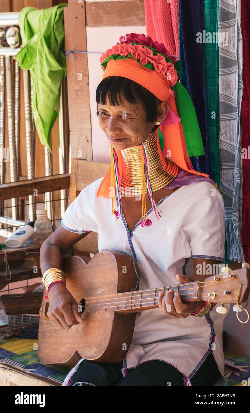 Una donna eldery dalla tribù Kayan indossando il tradizionale costume e collo in ottone anelli Kayan suonare la chitarra con quattro stringhe in Pan Pet, Loikaw, Myanmar. Foto Stock