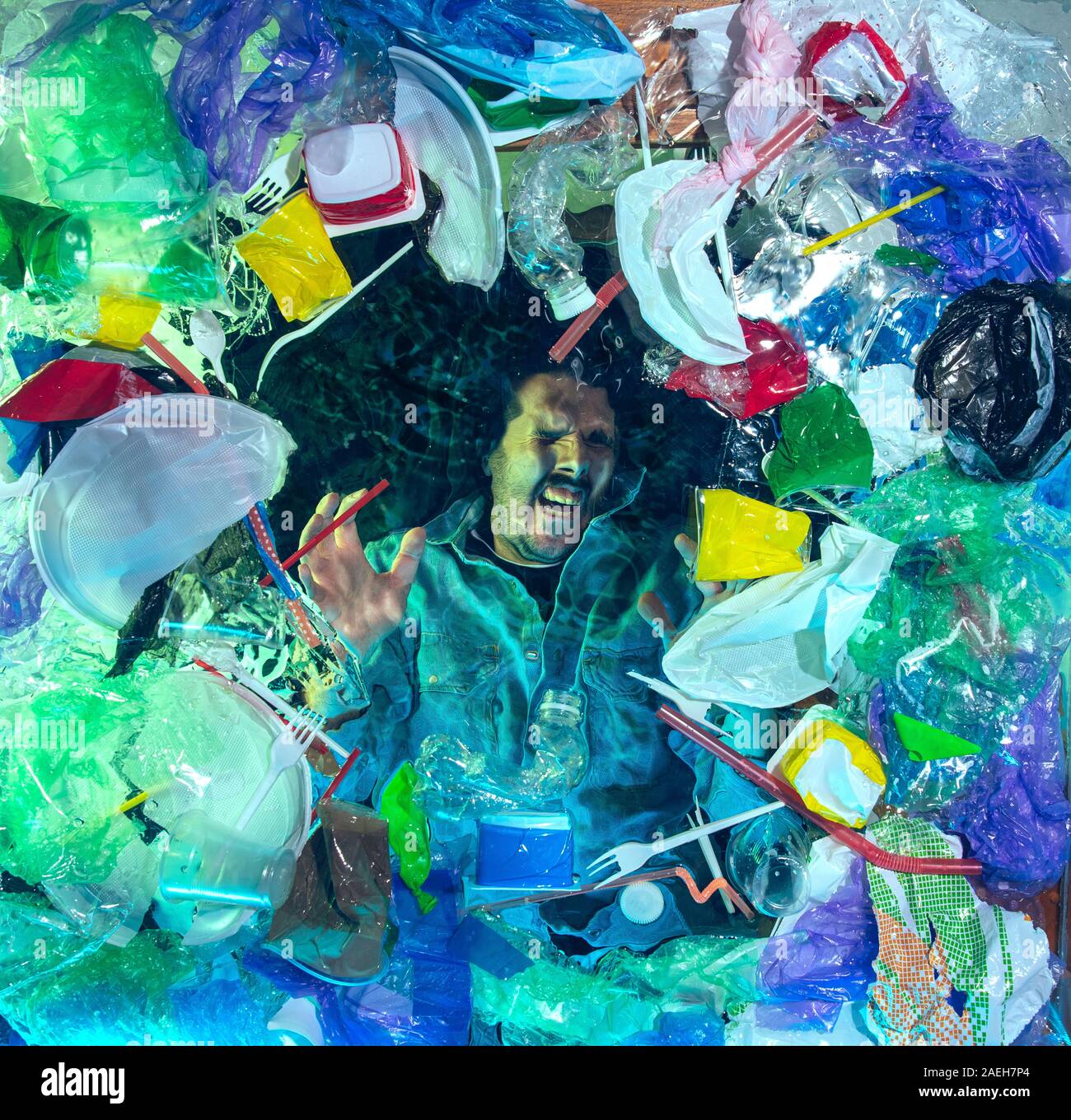 L'uomo annegamento in acqua sotto plastica destinatari pila, garbage. Utilizzate bottiglie e pacchi di riempimento oceano mondiale uccisione di persone. Ecologia, Ambiente concetto, plastica e vetro inquinamento, natura disastro. Foto Stock