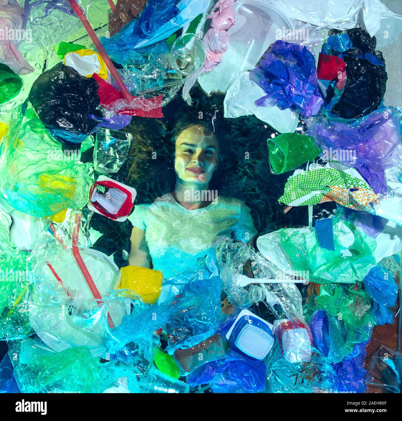 Donna annegamento in acqua sotto plastica destinatari pila, garbage. Utilizzate bottiglie e pacchi di riempimento oceano mondiale uccisione di persone. Ecologia, Ambiente concetto, plastica e vetro inquinamento, natura disastro. Foto Stock