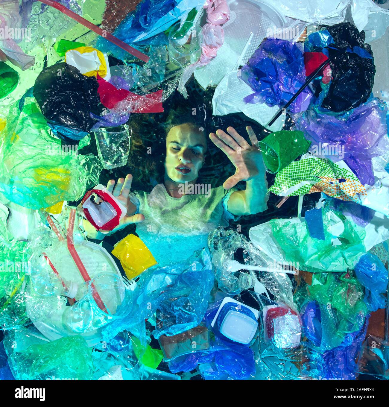 Donna annegamento in acqua sotto plastica destinatari pila, garbage. Utilizzate bottiglie e pacchi di riempimento oceano mondiale uccisione di persone. Ecologia, Ambiente concetto, plastica e vetro inquinamento, natura disastro. Foto Stock