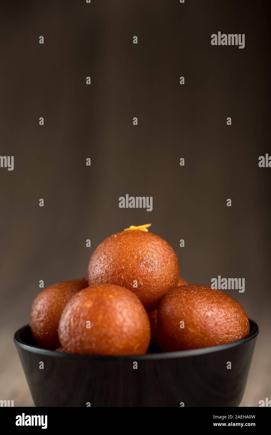 Indian dessert o un piatto dolce : Gulab Jamun in vaso su sfondo di legno. Foto Stock