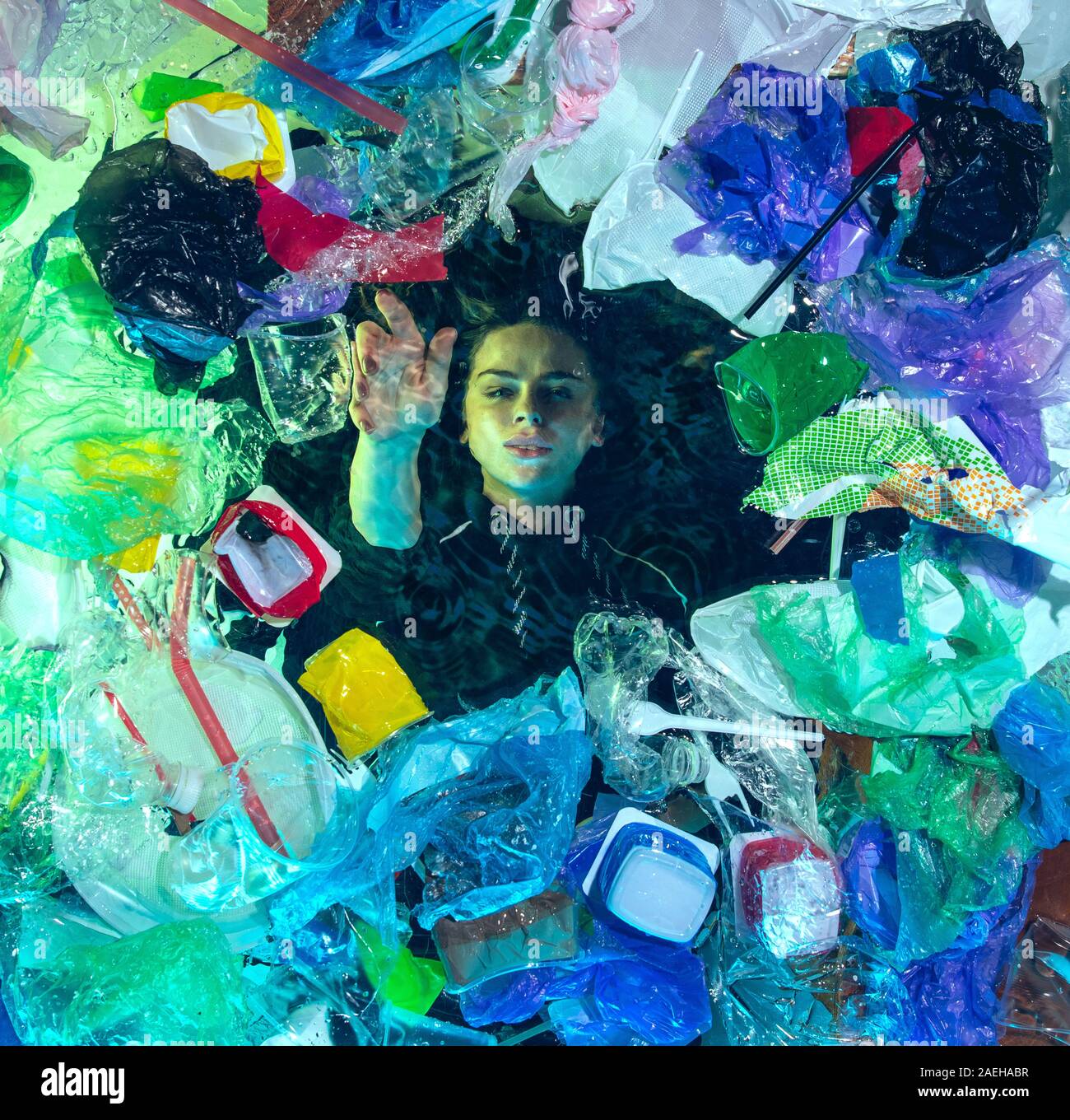 Donna annegamento in acqua sotto plastica destinatari pila, garbage. Utilizzate bottiglie e pacchi di riempimento oceano mondiale uccisione di persone. Ecologia, Ambiente concetto, plastica e vetro inquinamento, natura disastro. Foto Stock