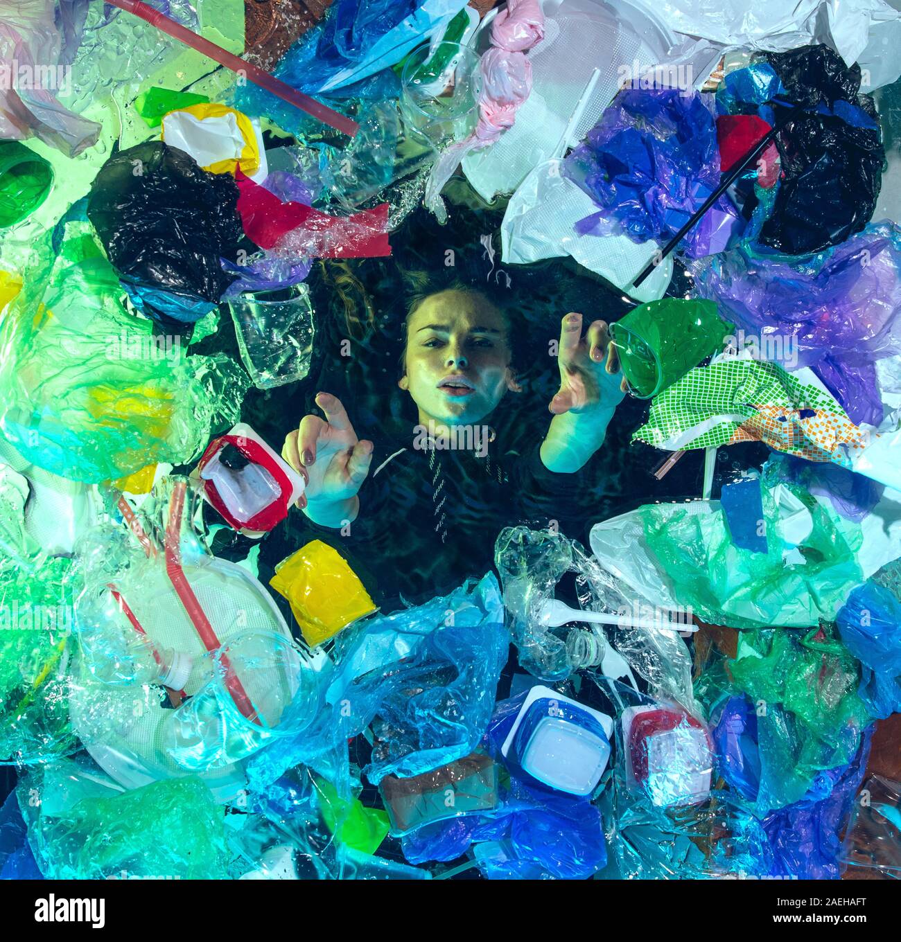 Donna annegamento in acqua sotto plastica destinatari pila, garbage. Utilizzate bottiglie e pacchi di riempimento oceano mondiale uccisione di persone. Ecologia, Ambiente concetto, plastica e vetro inquinamento, natura disastro. Foto Stock