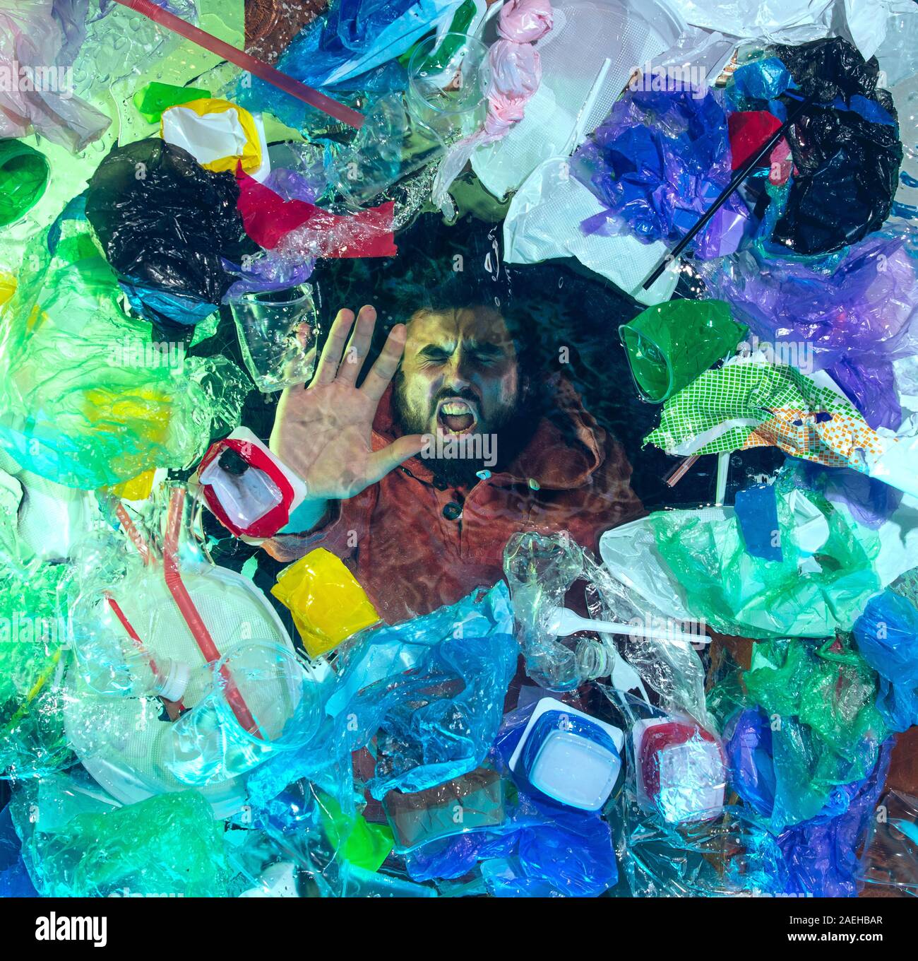 L'uomo annegamento in acqua sotto plastica destinatari pila, garbage. Utilizzate bottiglie e pacchi di riempimento oceano mondiale uccisione di persone. Ecologia, Ambiente concetto, plastica e vetro inquinamento, natura disastro. Foto Stock