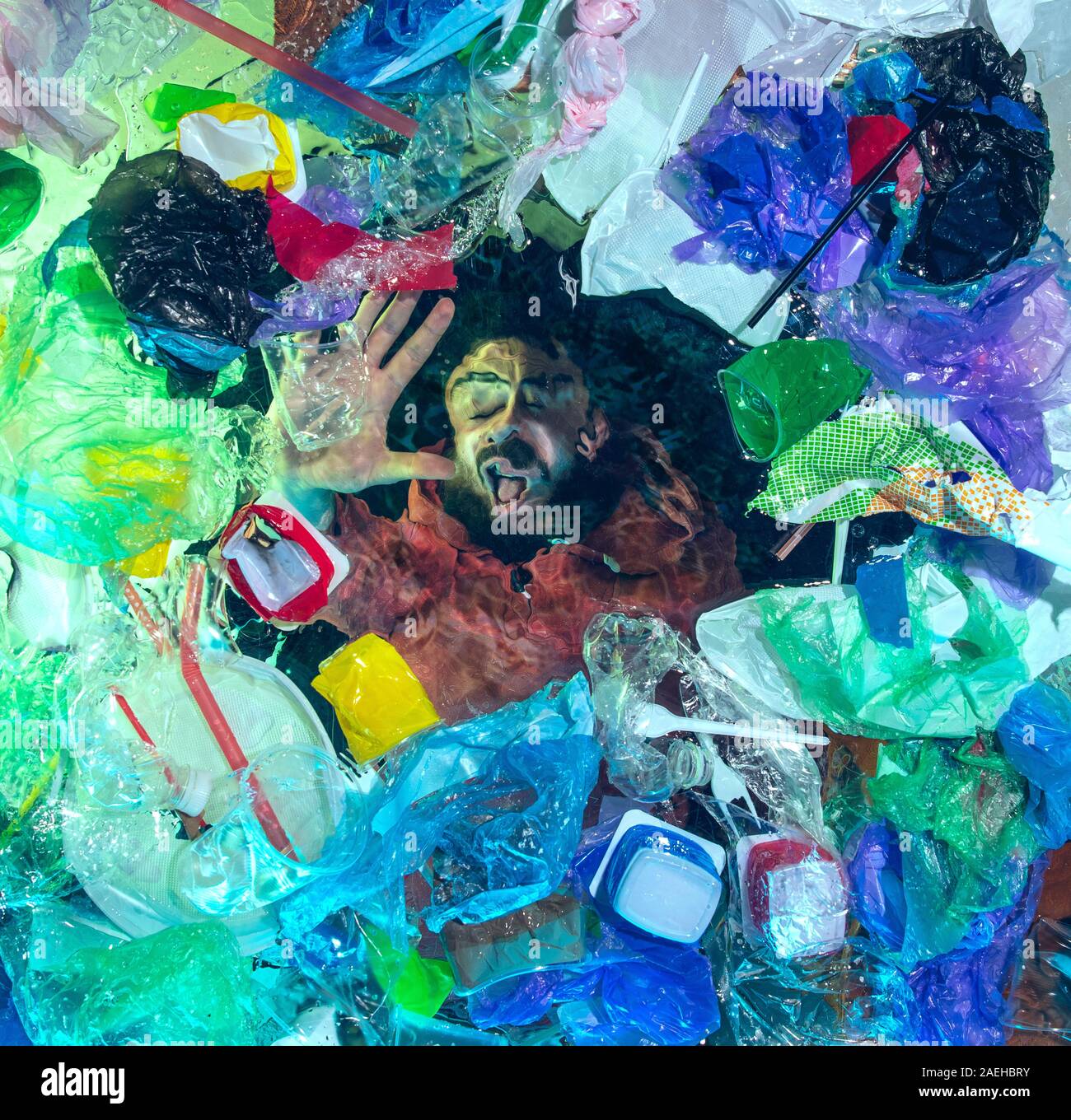 L'uomo annegamento in acqua sotto plastica destinatari pila, garbage. Utilizzate bottiglie e pacchi di riempimento oceano mondiale uccisione di persone. Ecologia, Ambiente concetto, plastica e vetro inquinamento, natura disastro. Foto Stock