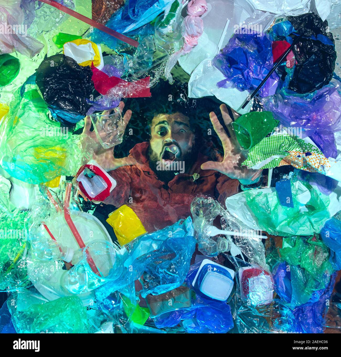 L'uomo annegamento in acqua sotto plastica destinatari pila, garbage. Utilizzate bottiglie e pacchi di riempimento oceano mondiale uccisione di persone. Ecologia, Ambiente concetto, plastica e vetro inquinamento, natura disastro. Foto Stock