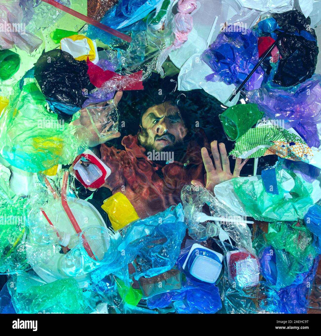 L'uomo annegamento in acqua sotto plastica destinatari pila, garbage. Utilizzate bottiglie e pacchi di riempimento oceano mondiale uccisione di persone. Ecologia, Ambiente concetto, plastica e vetro inquinamento, natura disastro. Foto Stock