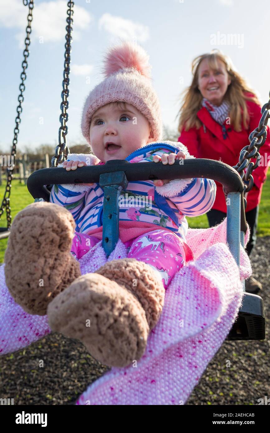 Donna spingendo un bambino su altalena Foto Stock