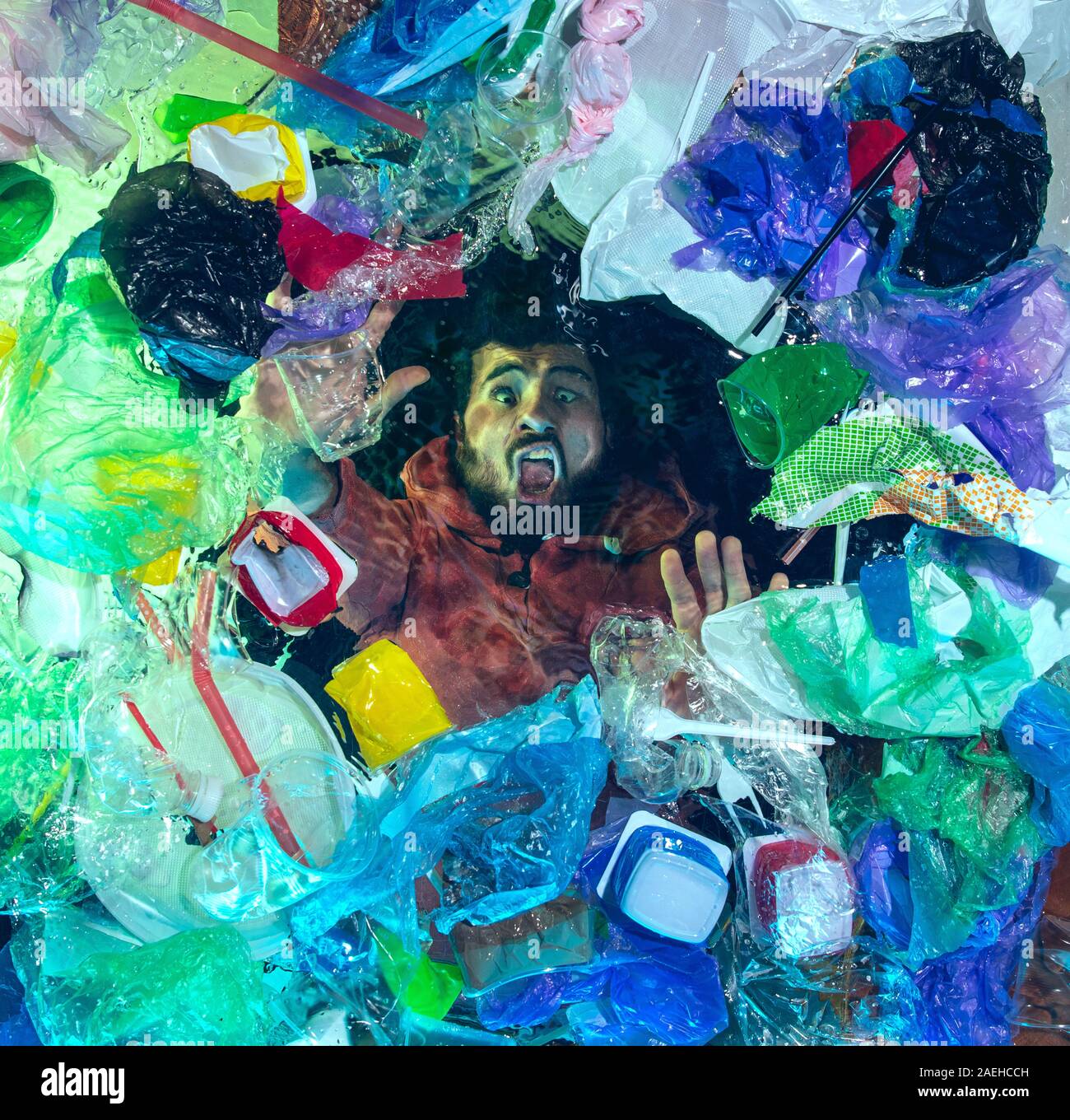 L'uomo annegamento in acqua sotto plastica destinatari pila, garbage. Utilizzate bottiglie e pacchi di riempimento oceano mondiale uccisione di persone. Ecologia, Ambiente concetto, plastica e vetro inquinamento, natura disastro. Foto Stock