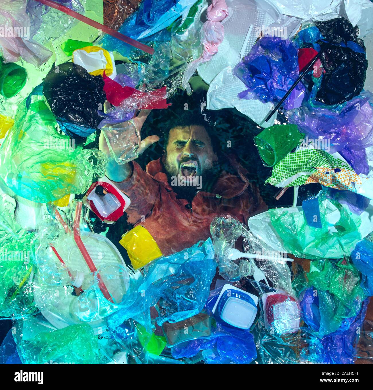 L'uomo annegamento in acqua sotto plastica destinatari pila, garbage. Utilizzate bottiglie e pacchi di riempimento oceano mondiale uccisione di persone. Ecologia, Ambiente concetto, plastica e vetro inquinamento, natura disastro. Foto Stock