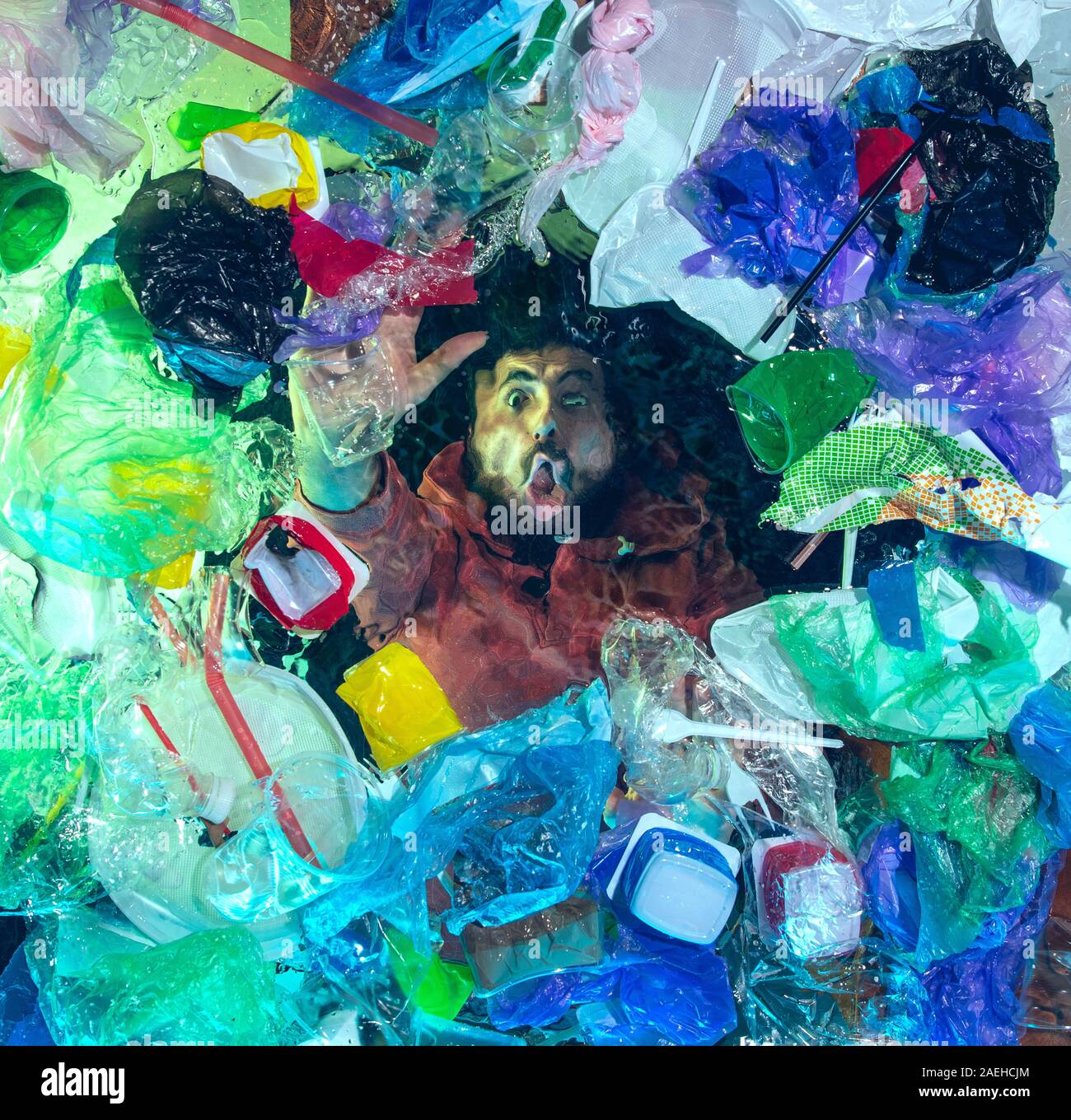 L'uomo annegamento in acqua sotto plastica destinatari pila, garbage. Utilizzate bottiglie e pacchi di riempimento oceano mondiale uccisione di persone. Ecologia, Ambiente concetto, plastica e vetro inquinamento, natura disastro. Foto Stock