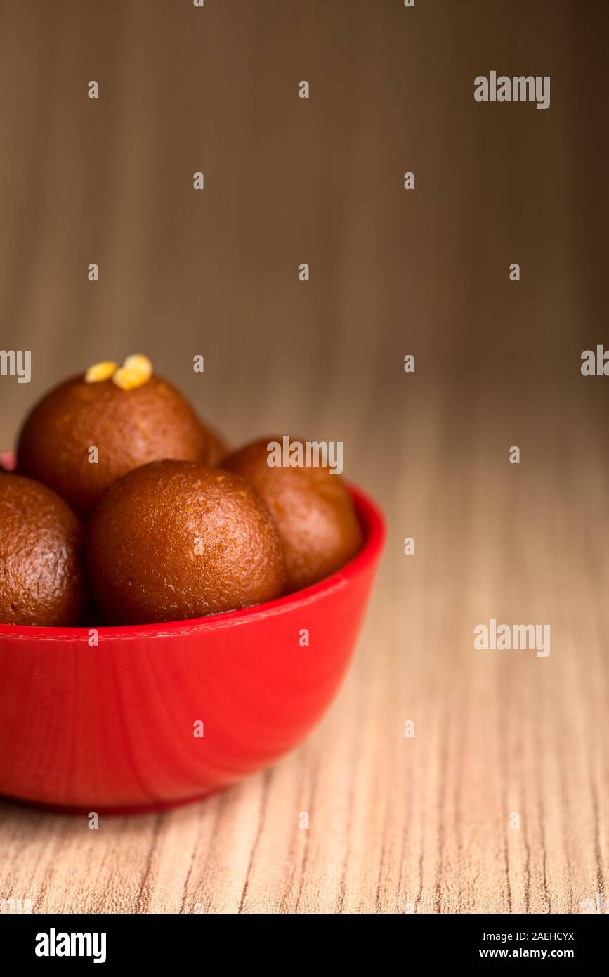 Gulab Jamun nel recipiente rosso su sfondo di legno. Indian dessert o un piatto dolce. Foto Stock