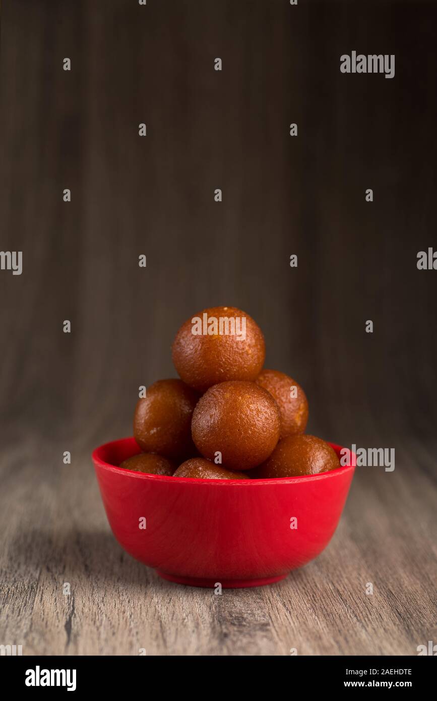 Gulab Jamun nel recipiente rosso su sfondo di legno. Indian dessert o un piatto dolce. Foto Stock