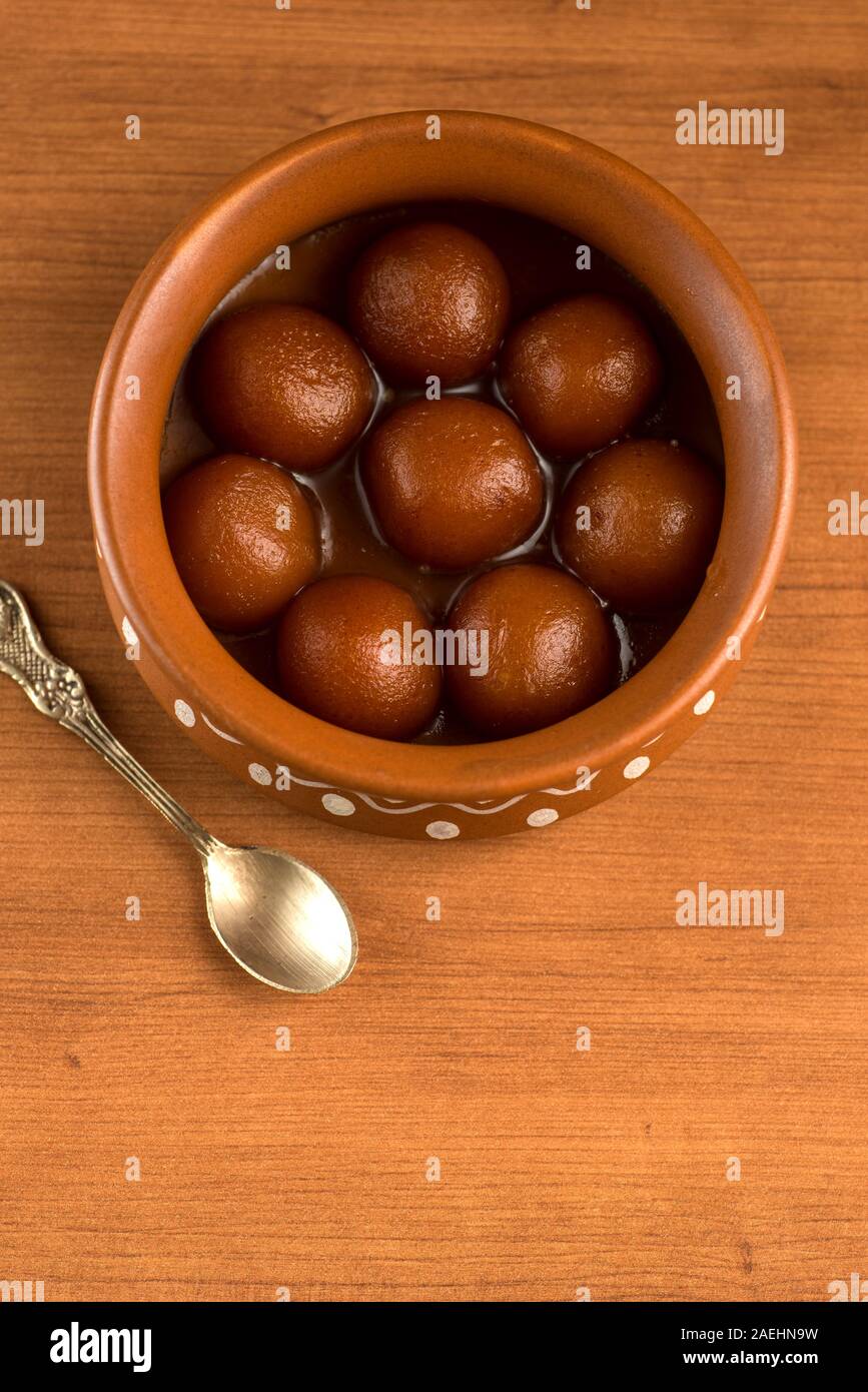 Gulab Jamun in pentola di creta con cucchiaio e frutta secca. Indian dessert o un piatto dolce Foto Stock