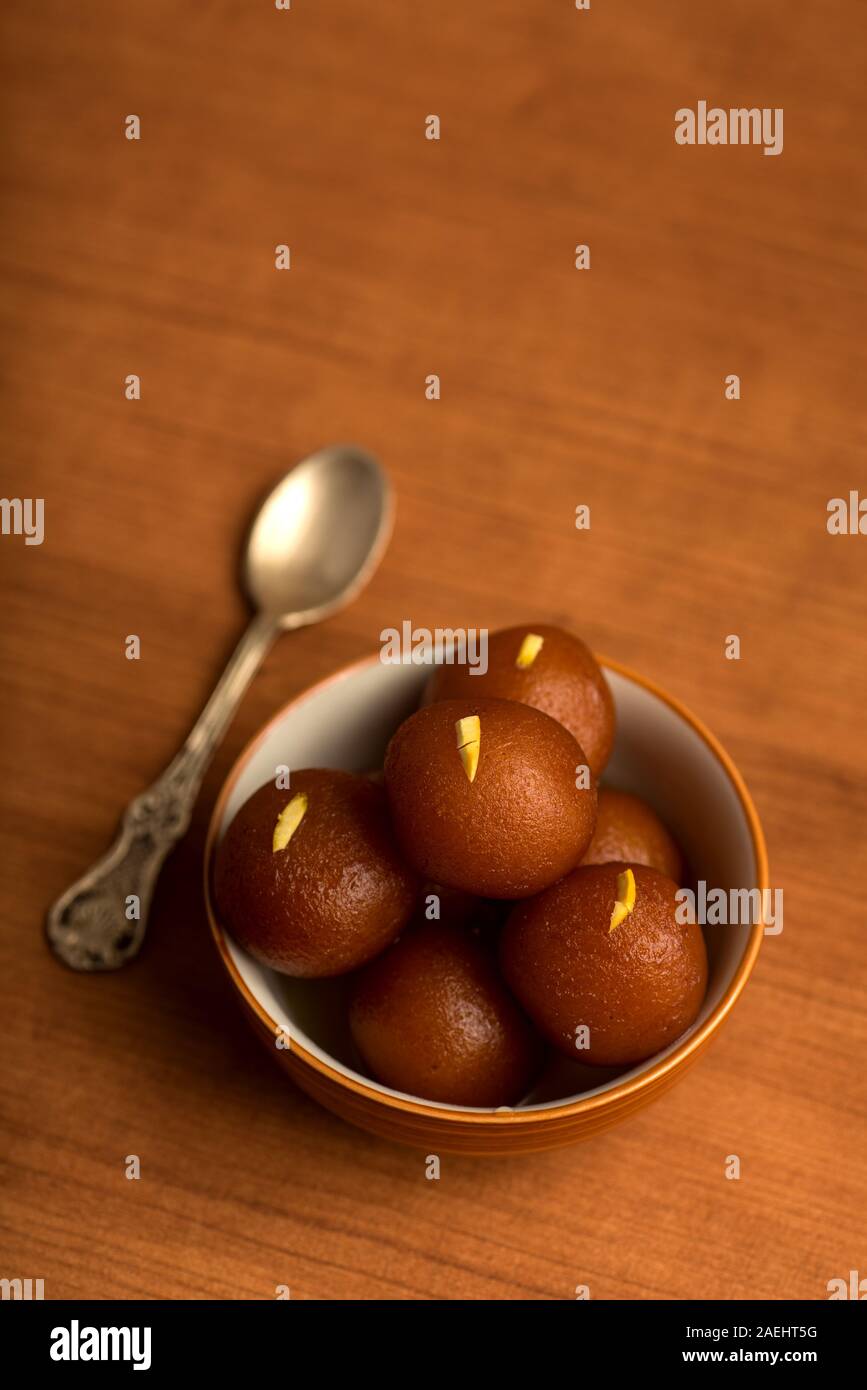 Gulab Jamun in vaso su sfondo di legno. Indian dessert o un piatto dolce. Foto Stock