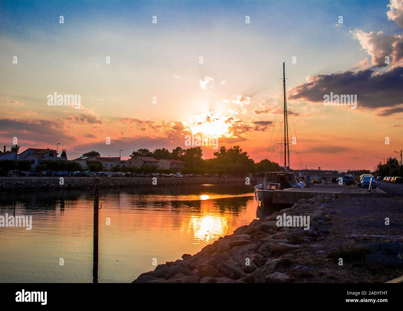 Vista di un porto, case presso la riva del fiume al tramonto e barche in attesa Foto Stock