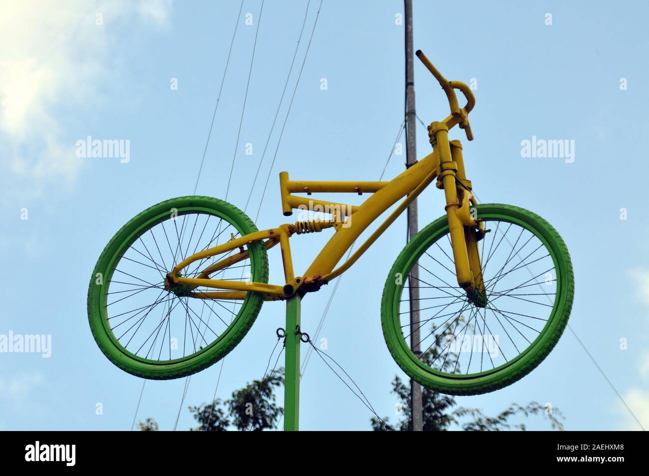 Una bicicletta verde e gialla sospesa in aria sopra un palo. Foto Stock