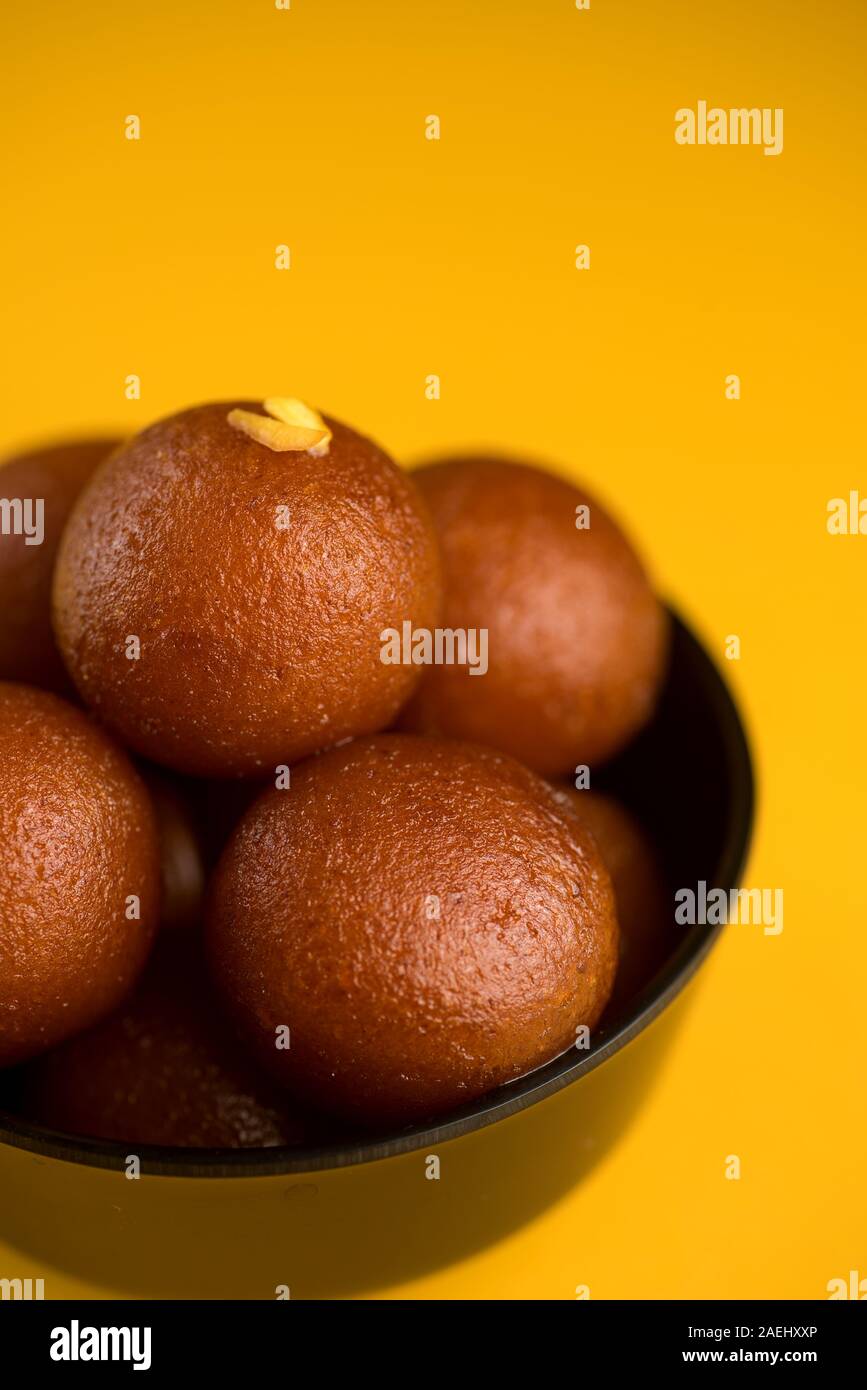 Indian dessert o un piatto dolce : Gulab Jamun nella ciotola su sfondo giallo. Foto Stock