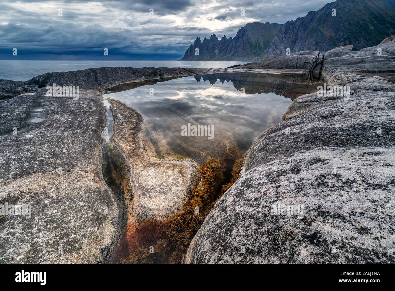 Costa a Tungeneset,vista sul famoso del diavolo picchi di denti formazione rocciosa di mountain range Okshornan, isola Senja, Troms, Norvegia settentrionale. Foto Stock