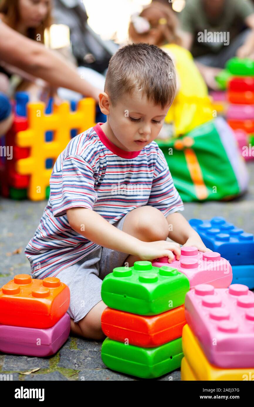 Carino ragazzo giocando con il giocattolo edili blocchi colorati. Il capretto con faccia felice giocando con mattoni di plastica. Plastica giocattolo di grandi dimensioni. Foto Stock